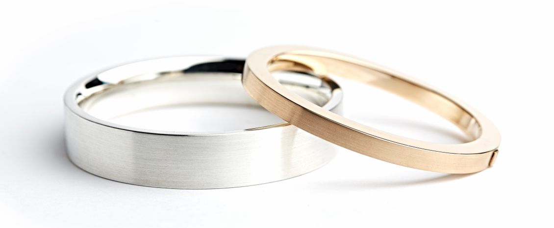 Zwei Armreifen, einer in Silber und einer in Rosegold.